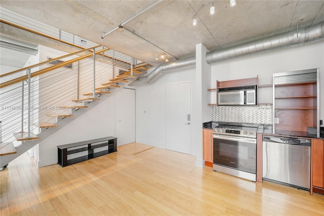 kitchen with tasteful backsplash, stainless steel appliances, and light hardwood / wood-style floors