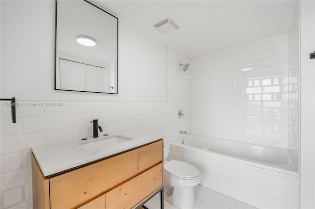 full bathroom featuring vanity, toilet, tiled shower / bath combo, and tile walls