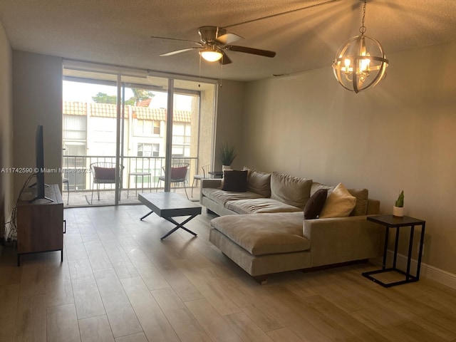 living room featuring ceiling fan with notable chandelier, floor to ceiling windows, hardwood / wood-style floors, and a textured ceiling