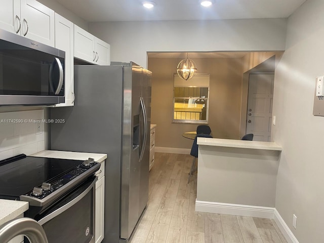 kitchen featuring white cabinetry, pendant lighting, light wood-type flooring, and appliances with stainless steel finishes