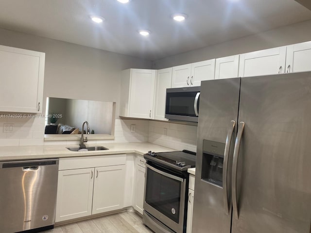 kitchen with stainless steel appliances, white cabinetry, sink, and backsplash