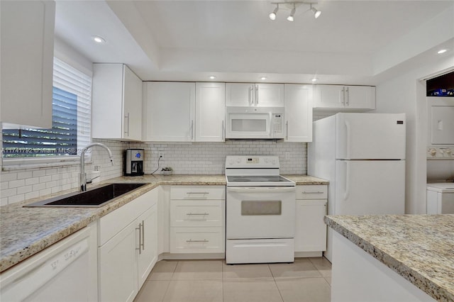 kitchen with stacked washer and dryer, white appliances, sink, tasteful backsplash, and white cabinets