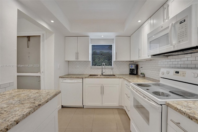 kitchen featuring tasteful backsplash, sink, white cabinets, a tray ceiling, and white appliances