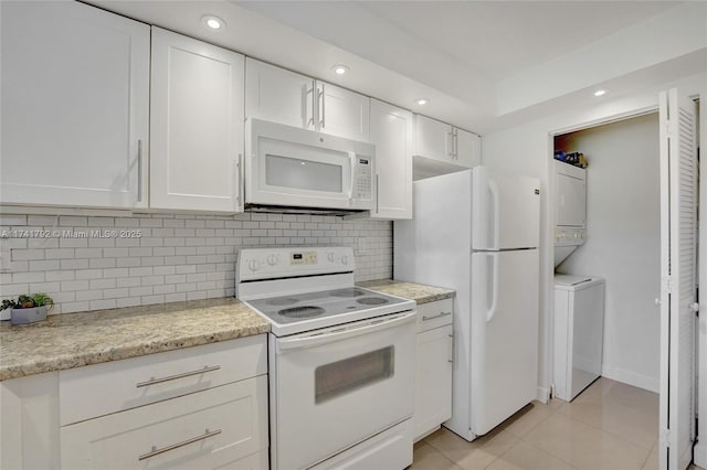 kitchen featuring stacked washer and dryer, white cabinetry, tasteful backsplash, light tile patterned floors, and white appliances