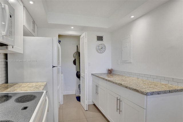 kitchen with light tile patterned floors, white appliances, white cabinetry, electric panel, and a raised ceiling