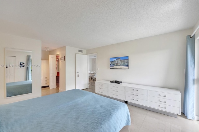 bedroom featuring a walk in closet, a textured ceiling, and light tile patterned floors