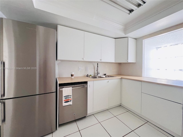 kitchen with a sink, white cabinetry, light countertops, appliances with stainless steel finishes, and crown molding