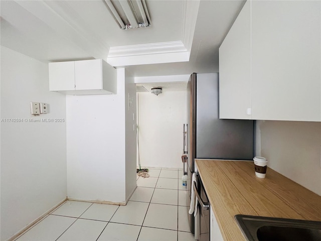 kitchen featuring white cabinetry, light tile patterned floors, and crown molding