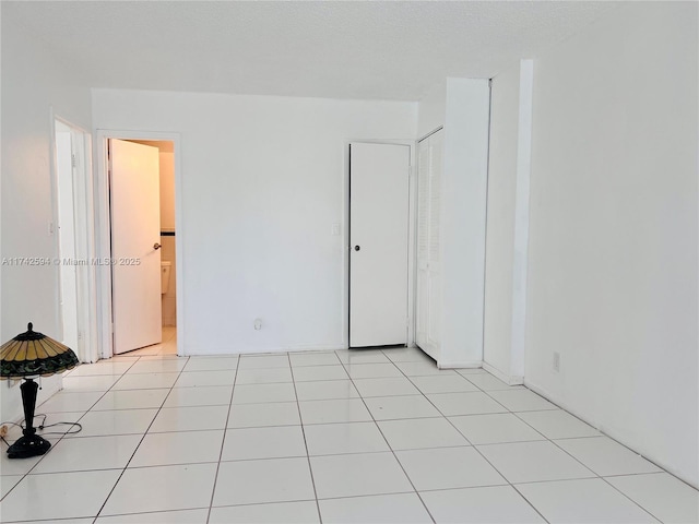 empty room featuring a textured ceiling and light tile patterned floors