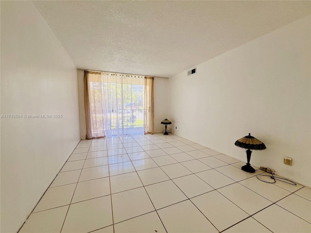 spare room with light tile patterned floors, a textured ceiling, and visible vents