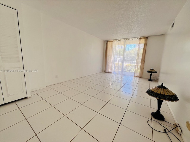 tiled spare room featuring a textured ceiling