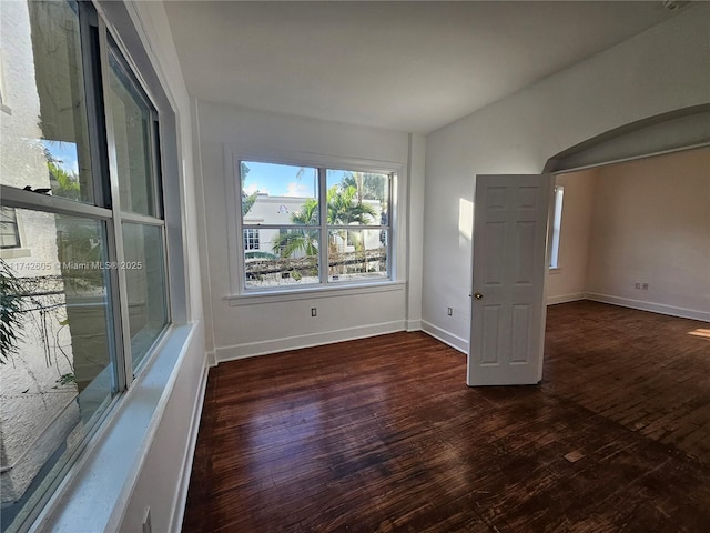 spare room with dark wood-type flooring and vaulted ceiling