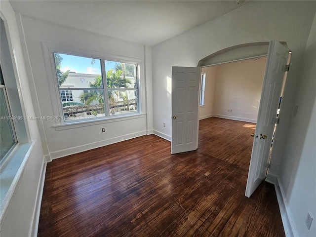 unfurnished room featuring vaulted ceiling and dark hardwood / wood-style floors