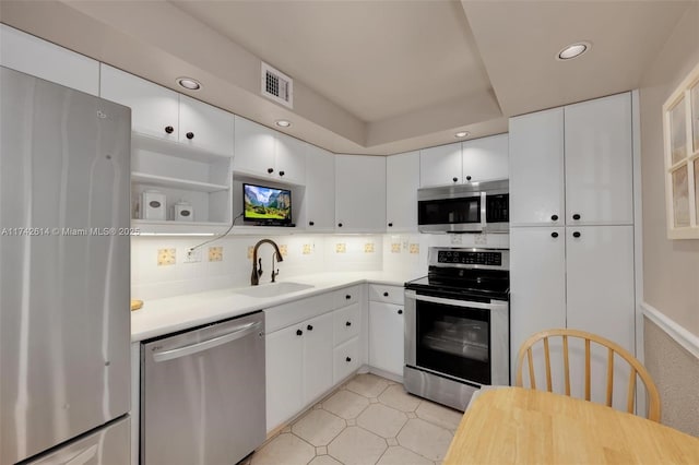 kitchen with tasteful backsplash, appliances with stainless steel finishes, sink, and white cabinets