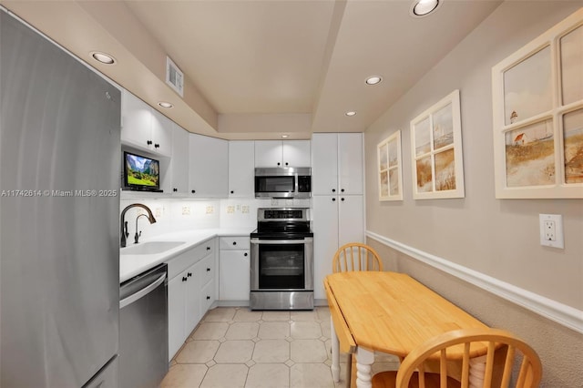 kitchen featuring light tile patterned flooring, appliances with stainless steel finishes, white cabinetry, sink, and decorative backsplash