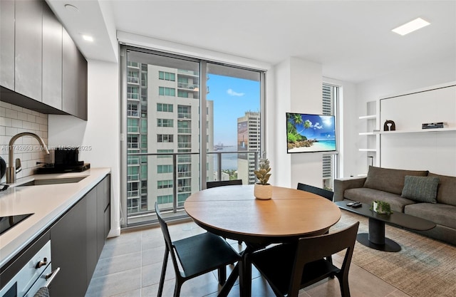 dining space featuring expansive windows, light tile patterned flooring, and sink