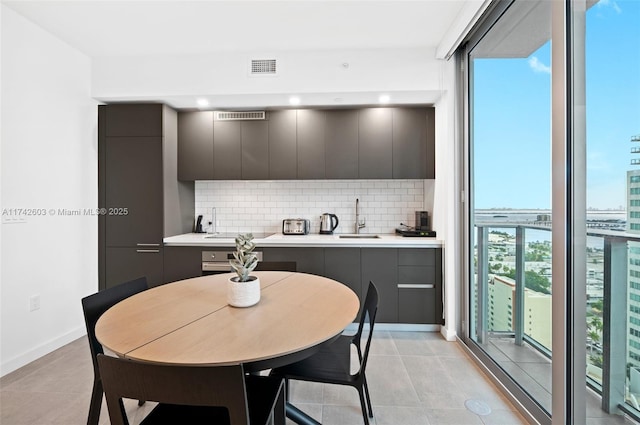 kitchen featuring tasteful backsplash, sink, light tile patterned floors, and oven