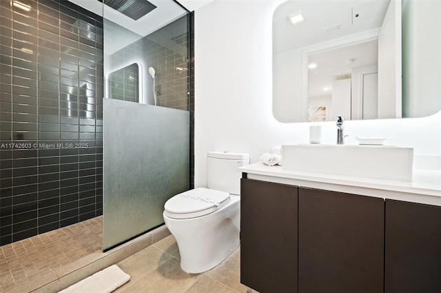 bathroom with vanity, toilet, tile patterned flooring, and a tile shower