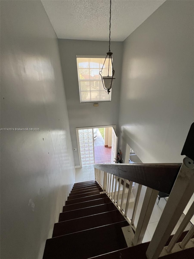 stairs featuring a towering ceiling and a textured ceiling