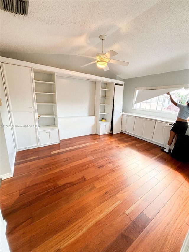 unfurnished bedroom featuring ceiling fan, light hardwood / wood-style flooring, a textured ceiling, and vaulted ceiling