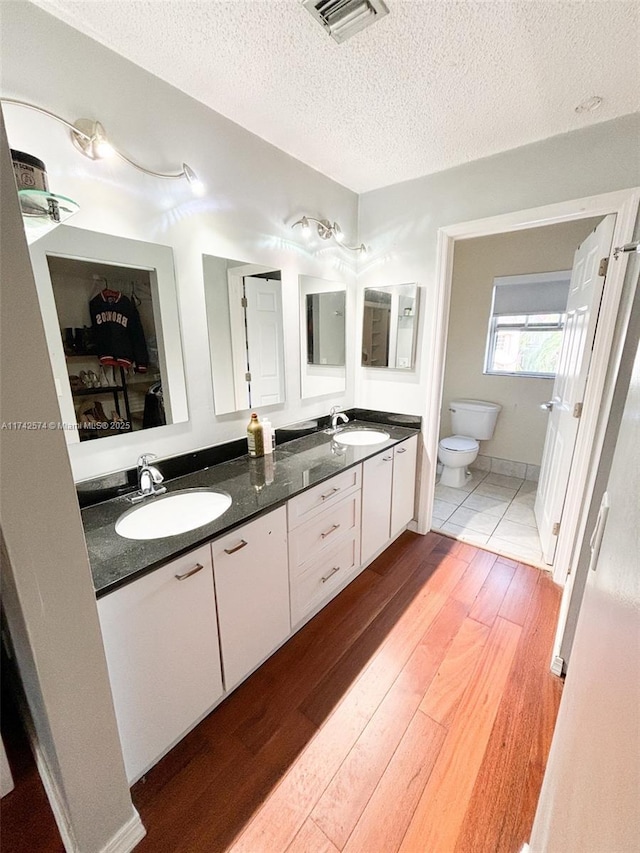 bathroom featuring vanity, toilet, hardwood / wood-style floors, and a textured ceiling