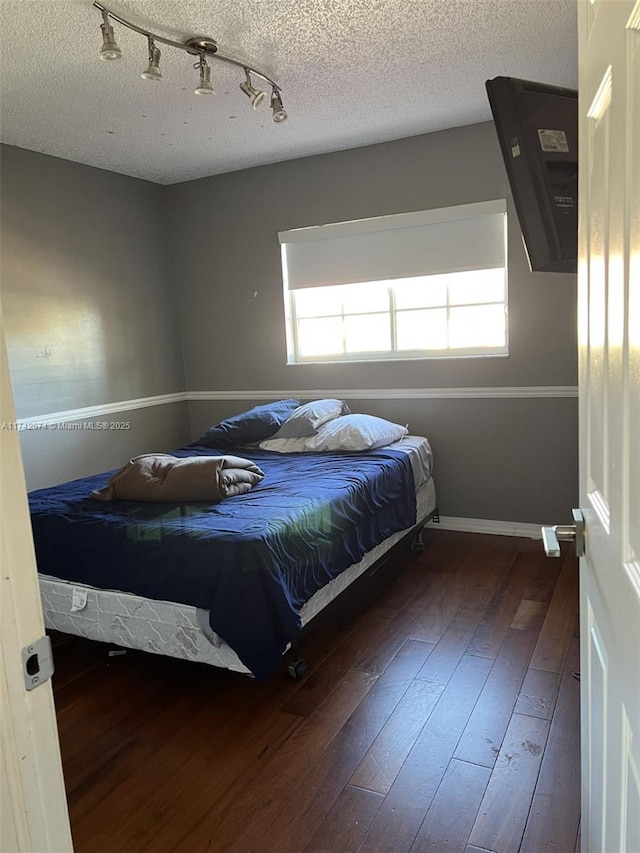 bedroom featuring dark hardwood / wood-style flooring and a textured ceiling