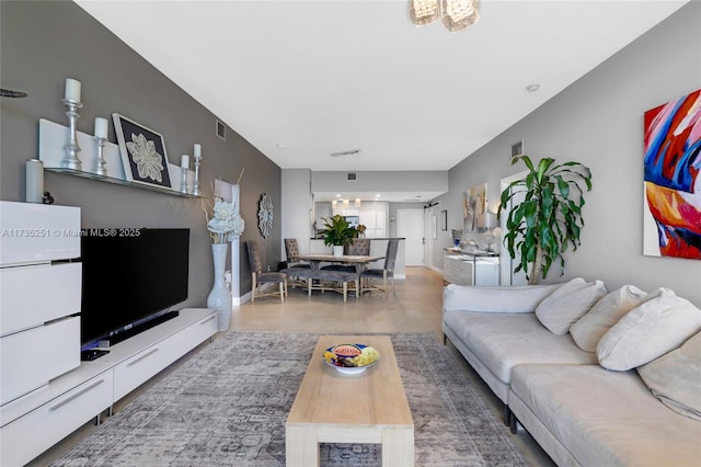 living area with baseboards, visible vents, and wood finished floors