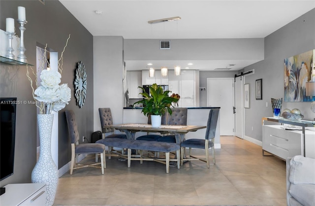 dining room with baseboards, a barn door, and visible vents