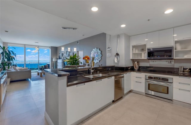 kitchen with open shelves, a peninsula, modern cabinets, a sink, and appliances with stainless steel finishes