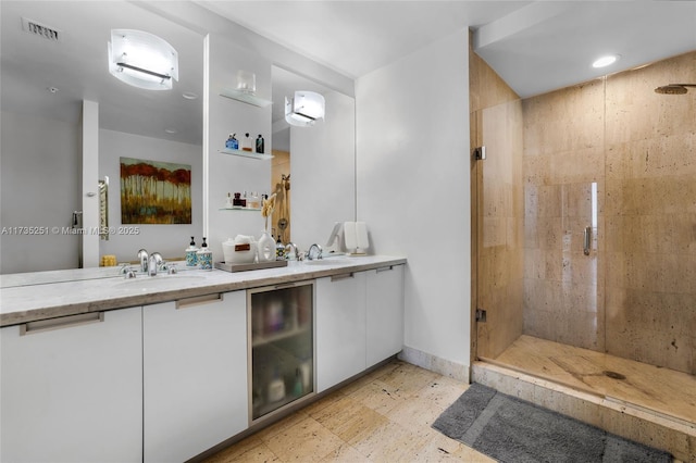 full bath with visible vents, a sink, double vanity, and a shower stall