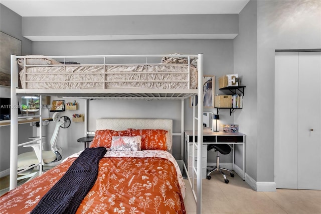bedroom with baseboards, tile patterned flooring, and a closet