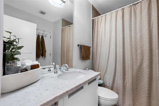 bathroom featuring vanity, toilet, and visible vents