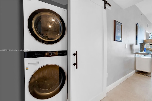 laundry room with stacked washer / drying machine, baseboards, and laundry area