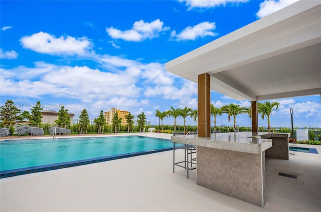 community pool featuring a patio and outdoor wet bar