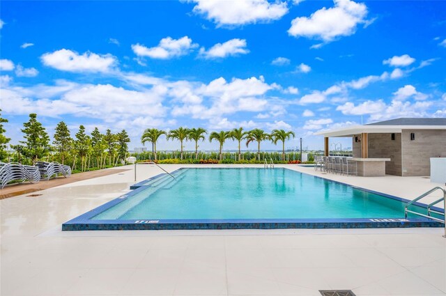 pool with outdoor dry bar and a patio area