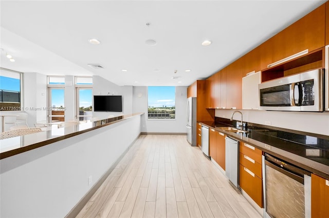 kitchen with brown cabinets, stainless steel appliances, a sink, and modern cabinets