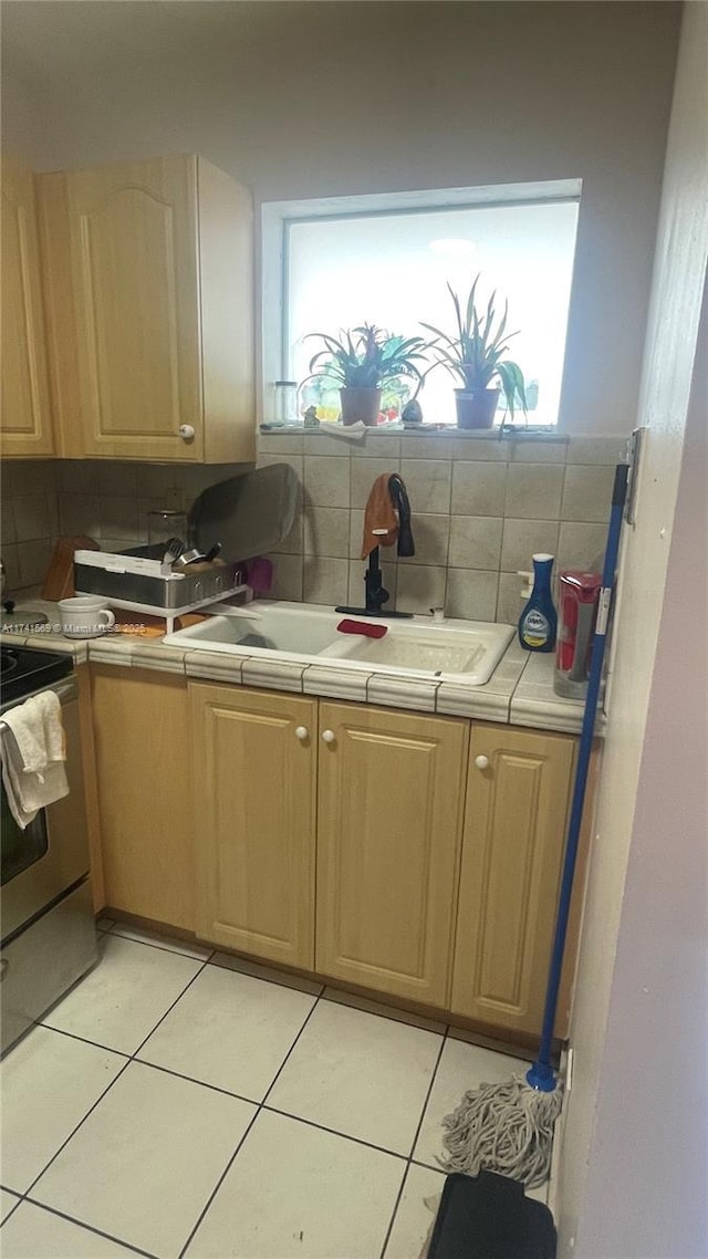 kitchen featuring light tile patterned flooring, stainless steel electric stove, sink, and backsplash