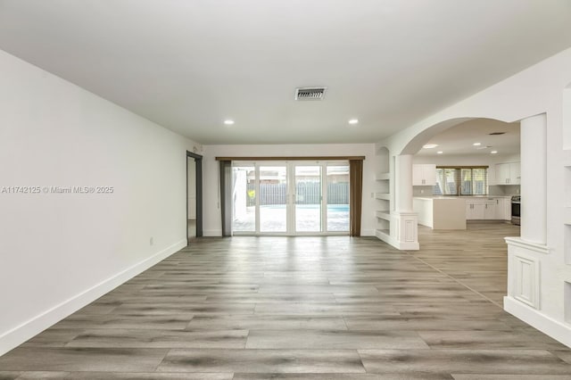 empty room with a healthy amount of sunlight, light wood-type flooring, and french doors