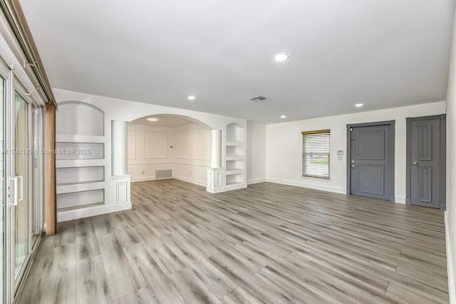 unfurnished living room featuring built in features and light hardwood / wood-style floors