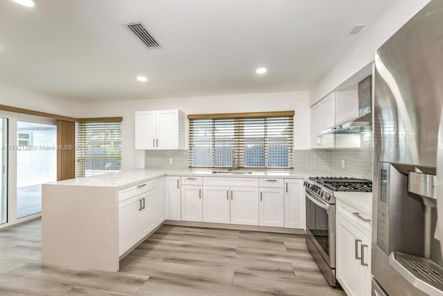 kitchen featuring tasteful backsplash, stainless steel appliances, kitchen peninsula, and white cabinets