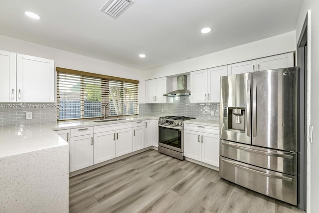 kitchen featuring wall chimney exhaust hood, white cabinetry, stainless steel appliances, and sink