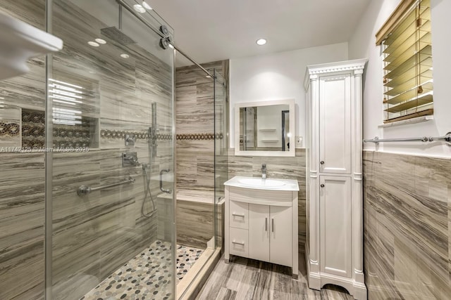 bathroom with vanity, a shower with door, and tile walls