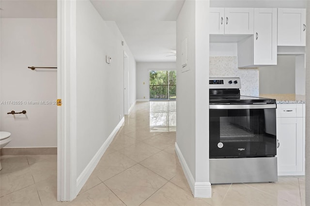 kitchen with electric stove, backsplash, light tile patterned floors, and white cabinets