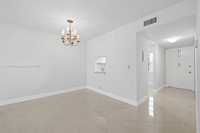 unfurnished room featuring a chandelier