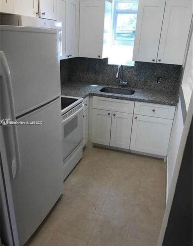 kitchen featuring white appliances, sink, and white cabinets