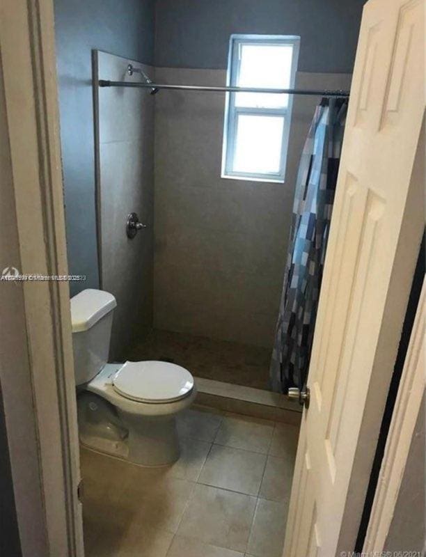 bathroom with tile patterned flooring, toilet, and a shower with shower curtain