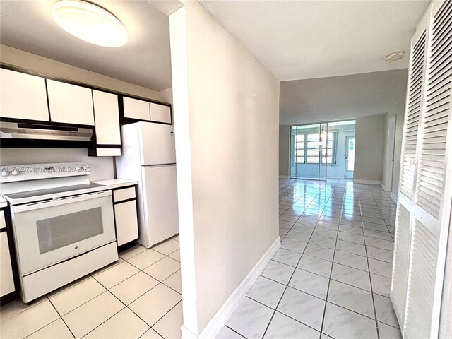 kitchen with white cabinetry, light tile patterned floors, and white appliances