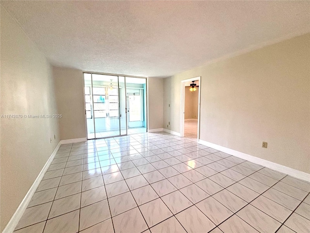 spare room featuring expansive windows, light tile patterned floors, and a textured ceiling