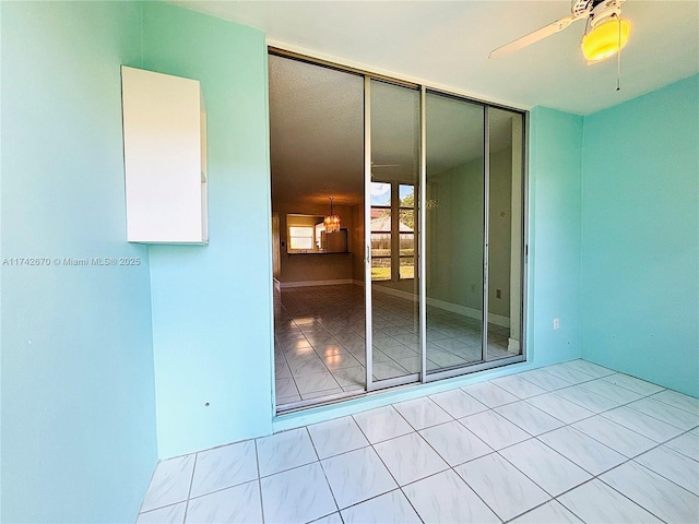 spare room with ceiling fan and light tile patterned floors