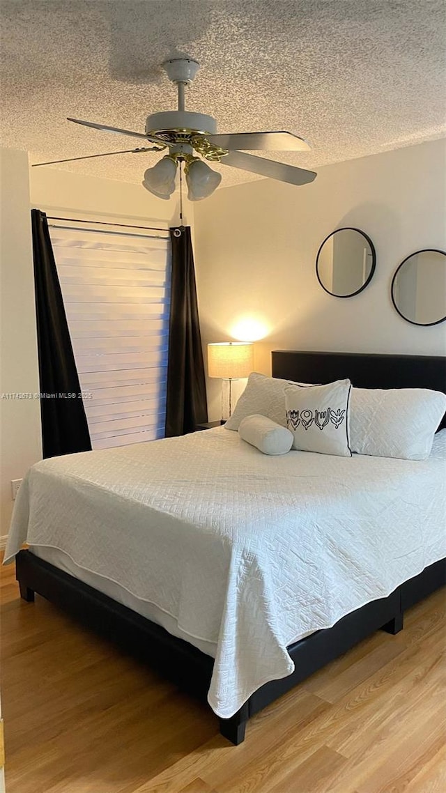 bedroom with ceiling fan, wood-type flooring, and a textured ceiling